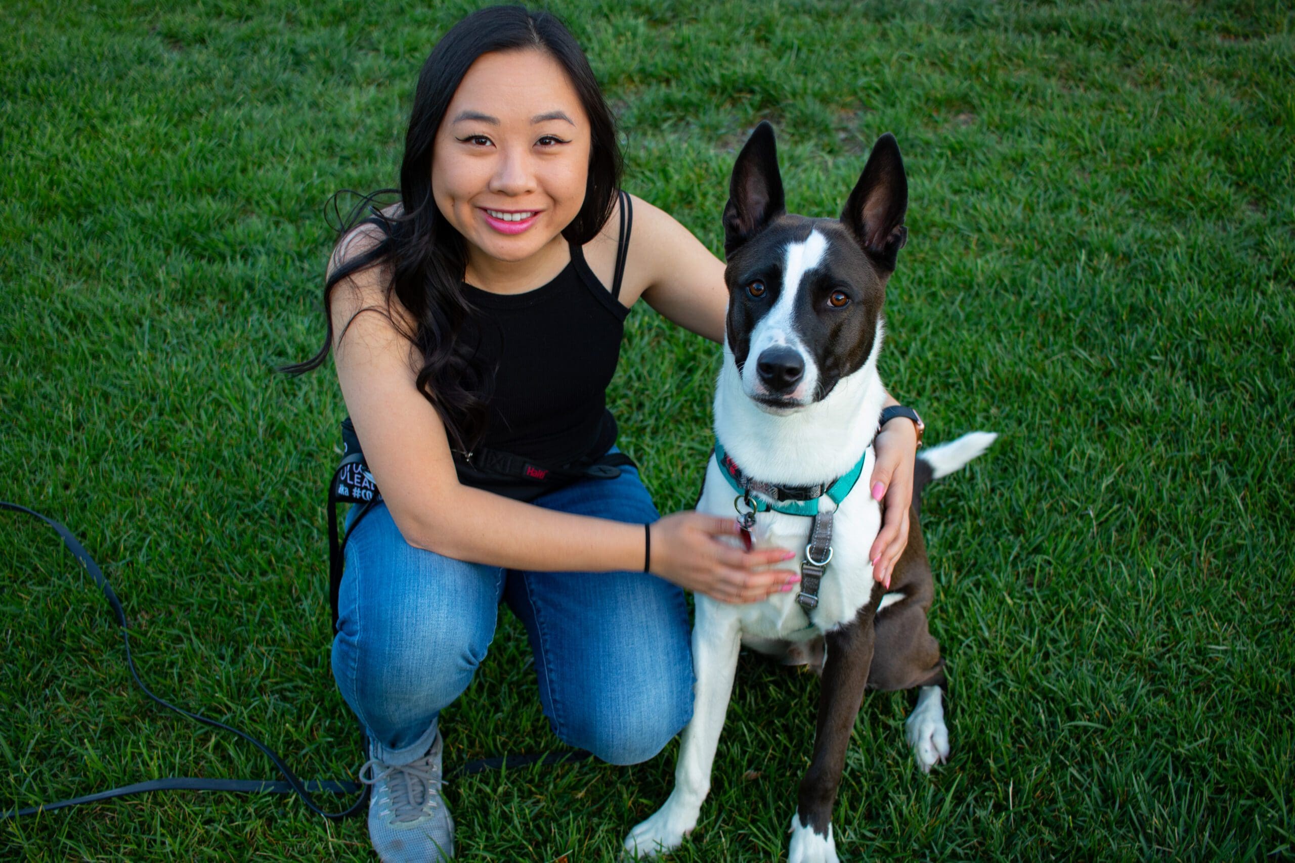An asian woman next to a black and white dog with pointy ears. Tiffany Chen of Pawsistant, social media manager.