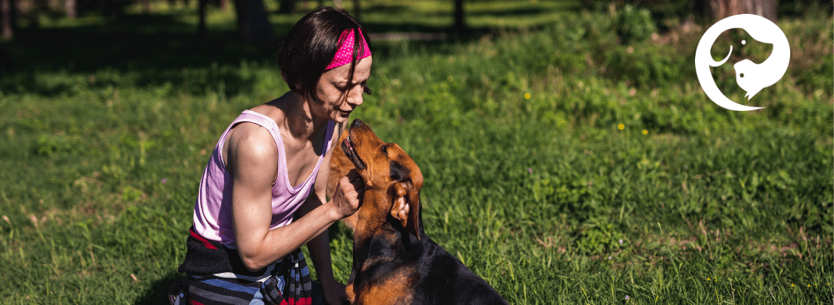 A brown dog next to a kneeling person, looking at each other, sharing a calm moment