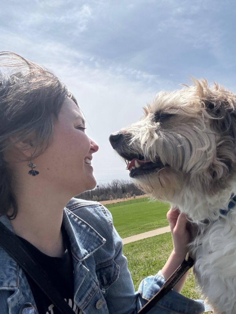 A fluffy brown and white dog looking at his person's face.