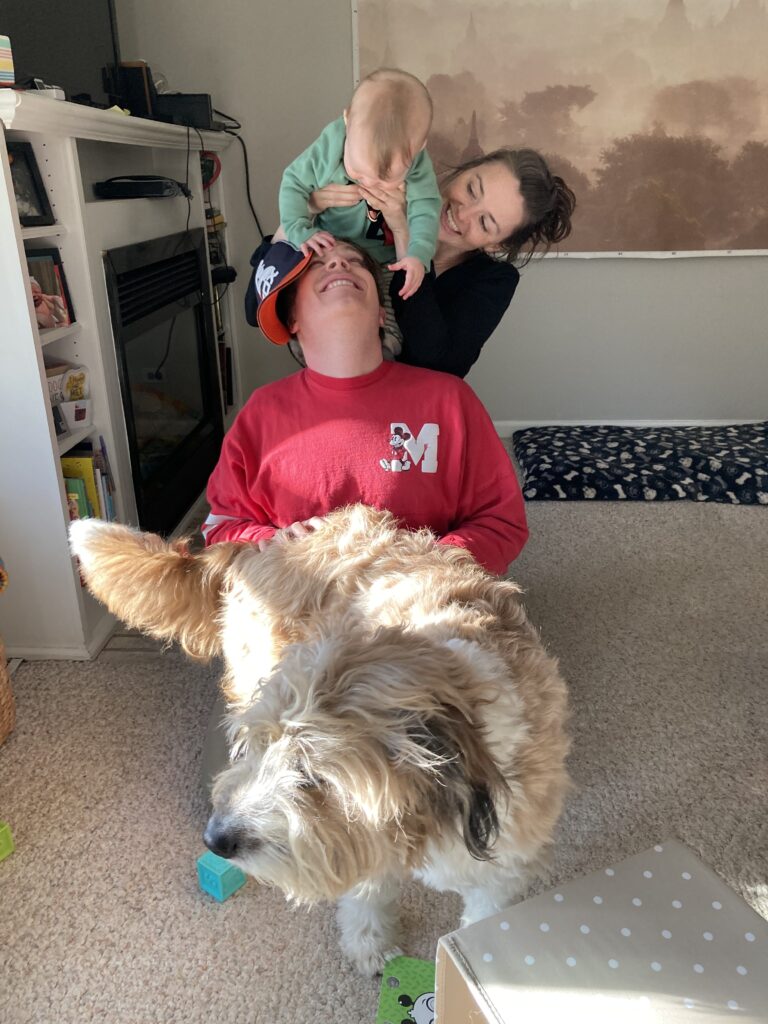 A fluffy brown and white dog with his family sitting behind him.