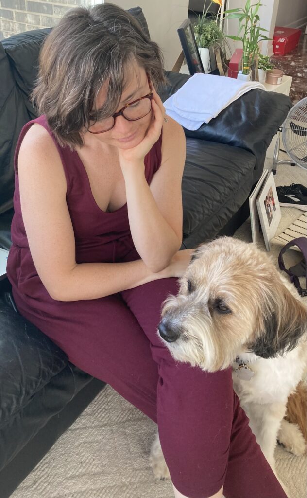 A fluffy brown and white dog with his head on his person's knee.
