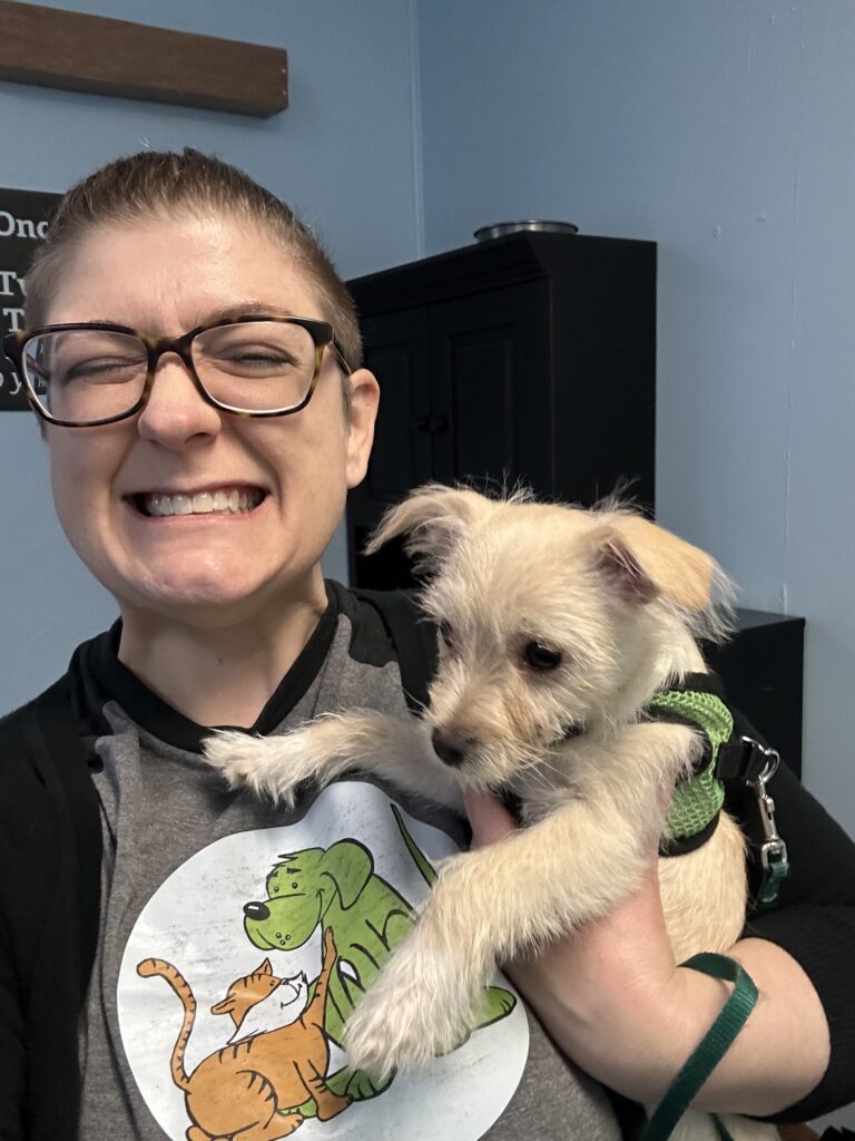 A woman holding a small scruffy puppy. Tiffany Holmes, dog trainer, working with a dog in Fort Wayne, Indiana