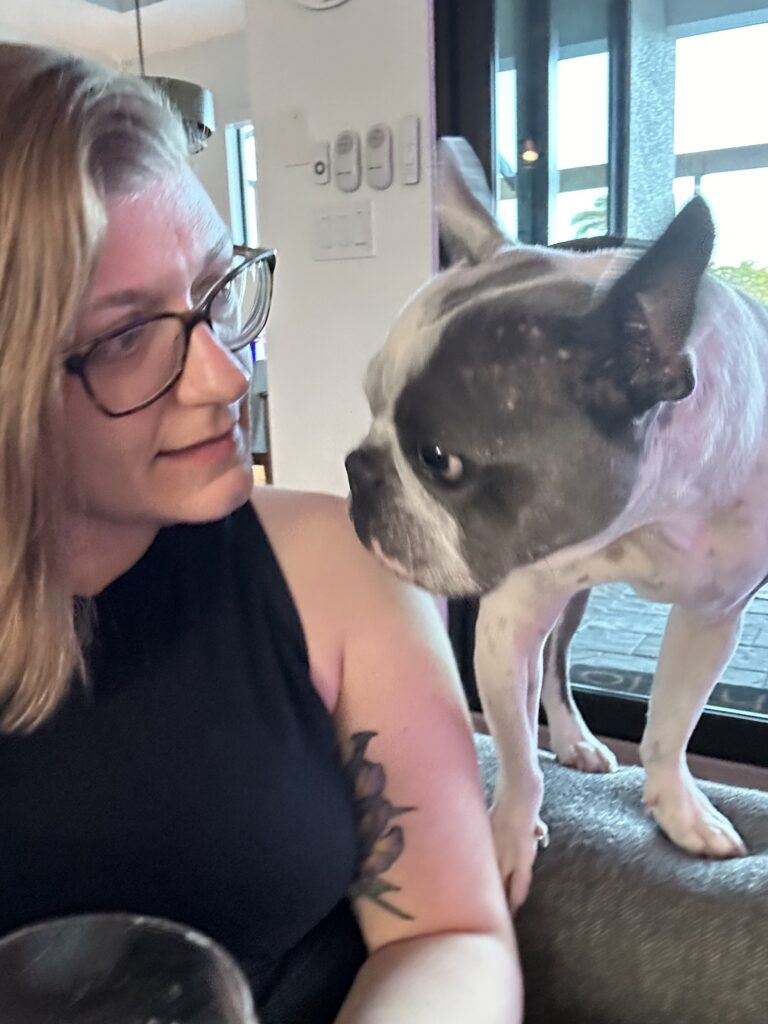 A woman having a conversation with a small frenchie.