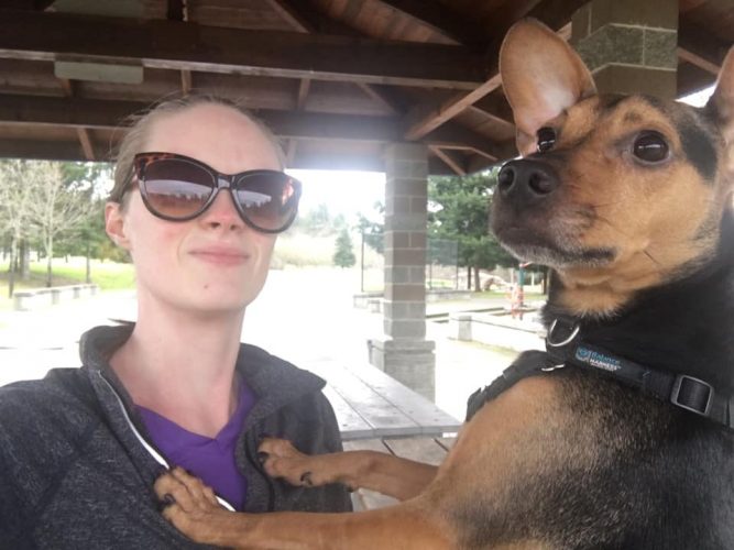 A beautiful lady in sunglasses next to a black and brown dog with large ears.