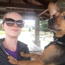 A beautiful lady in sunglasses next to a black and brown dog with large ears.